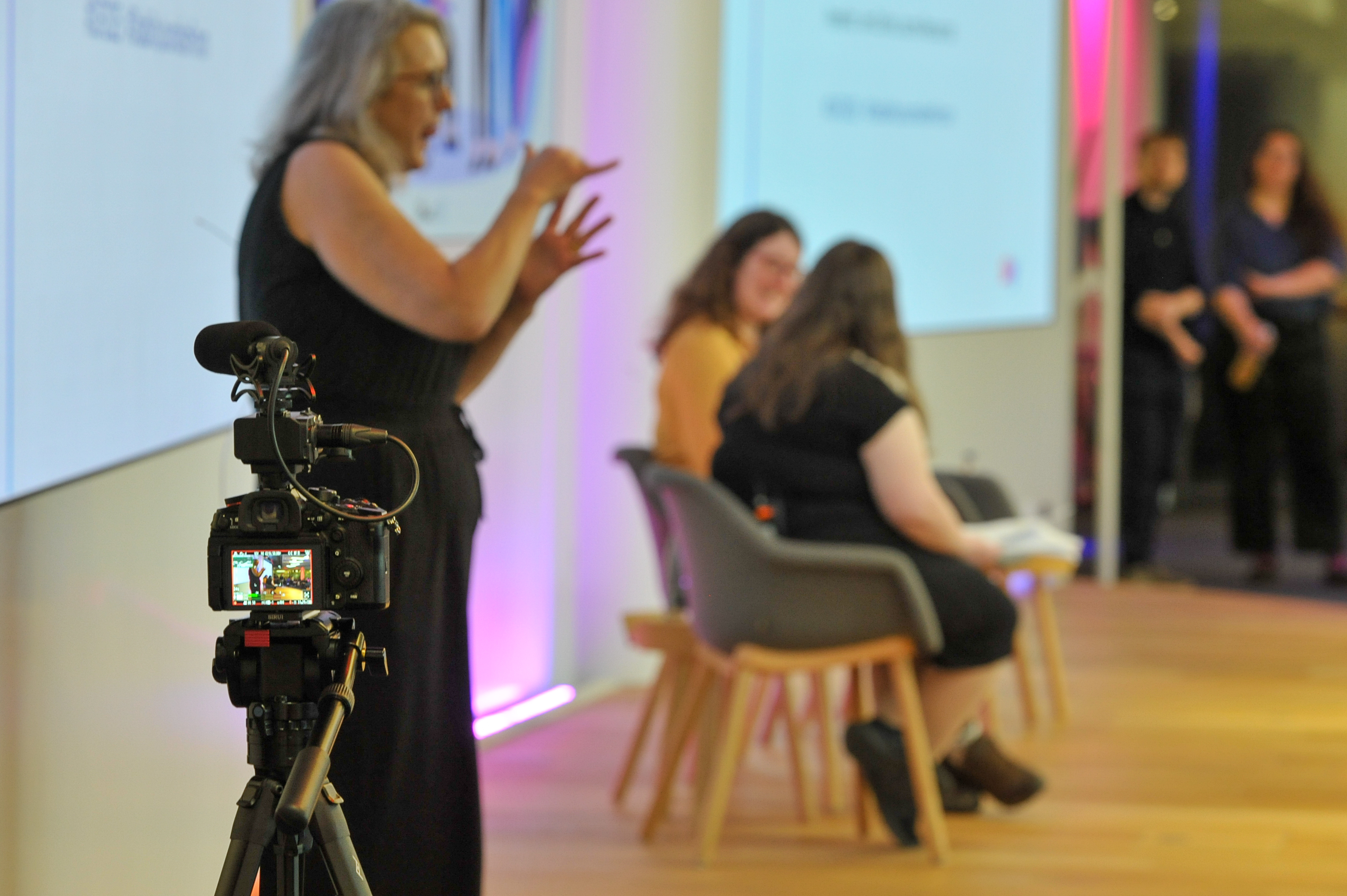 BSL interpreter on stage with speakers at an event